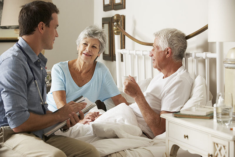 Hospice physician talking with elderly patient and spouse