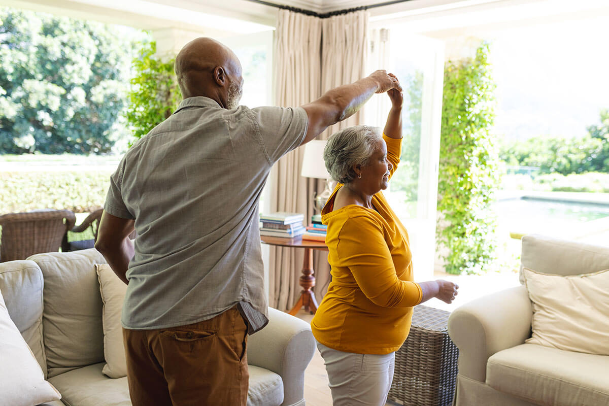 senior african american couple dancing together in living room